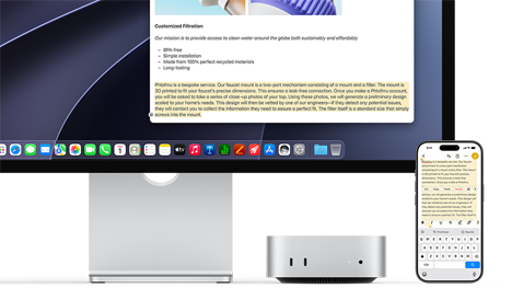 Mac mini front, tucked under Studio Display, an iPhone sits to the right of the device and the display, text selected with cut, copy, paste and AutoFill commands above on iPhone matches highlighted text on display, showcasing Universal Clipboard