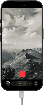 iPhone 18 Pro, front exterior, displaying a mountainous landscape, with the camera mode overlay in Time-Lapse mode, with charging cable attached to charging port