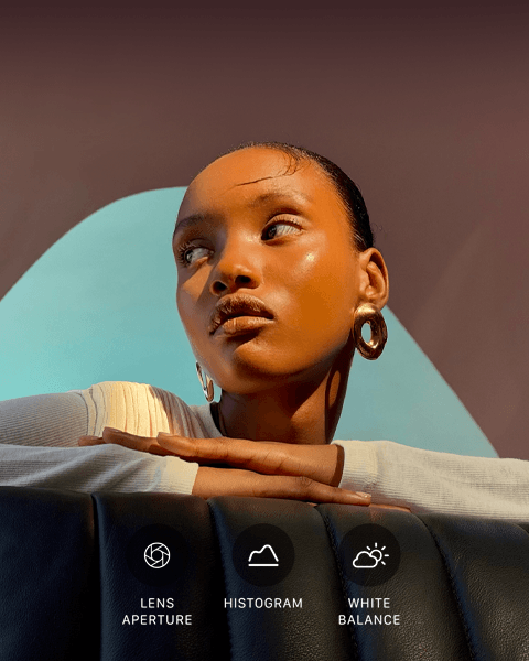 Close up portrait of a well-lit model with a colourful background, demonstrating the pro camera system's Pro controls UI: Lens Aperture, Histogram, White Balance